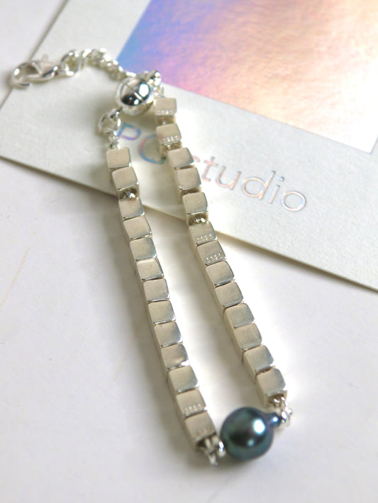 Silver bracelet for men with black Tahitian pearl on a white surface