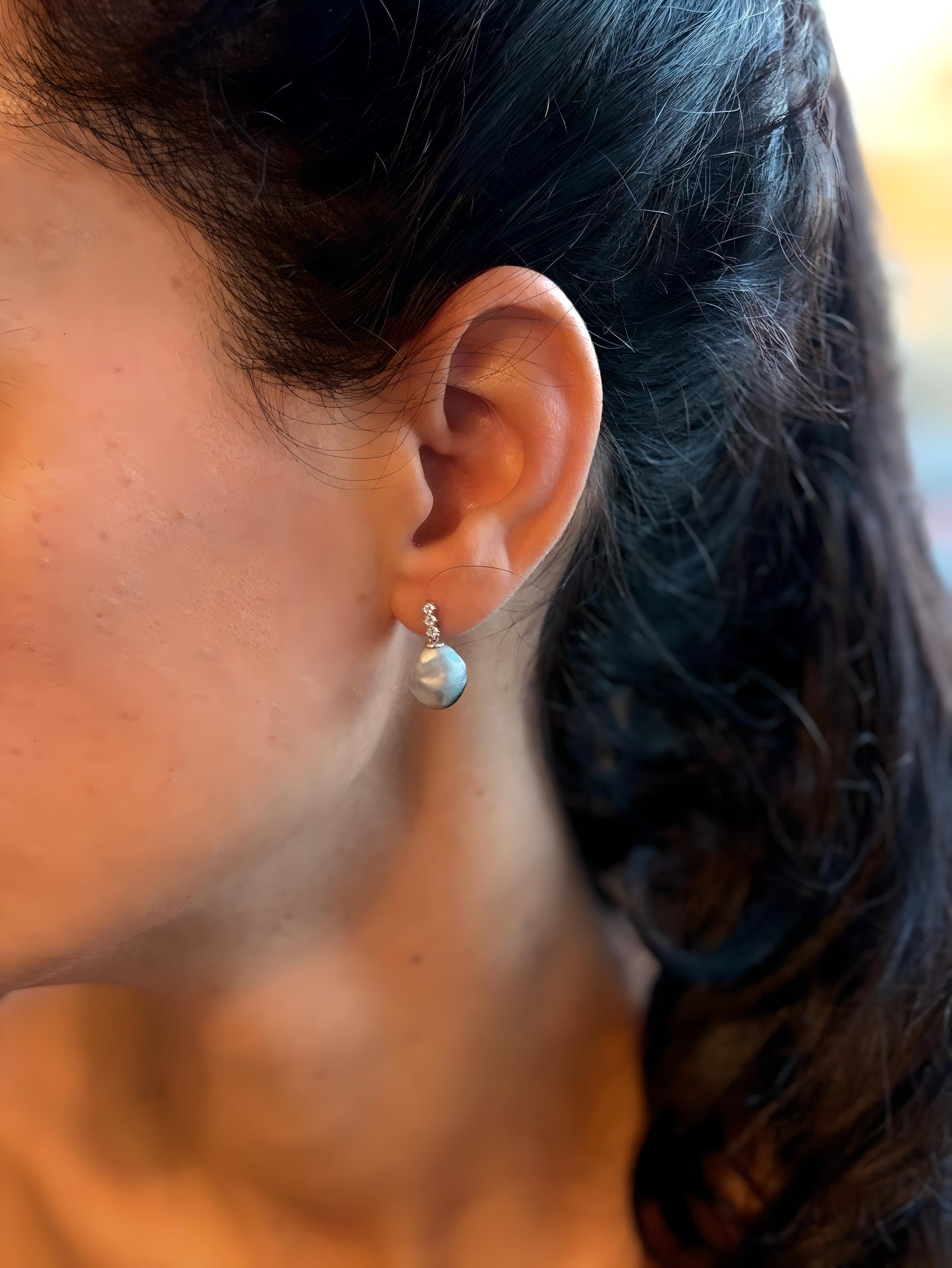 Close-up of women wearing a Tahitian Keshi pearl earrings with blurred background