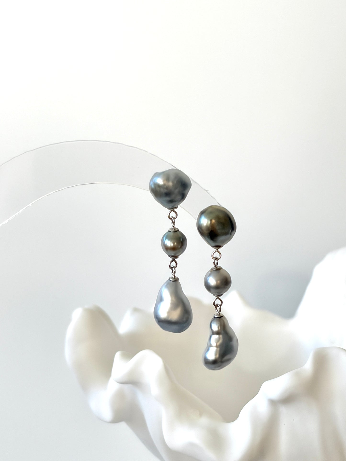 Pair of silver Tahitian Keshi Baroque pearl earrings on a white background