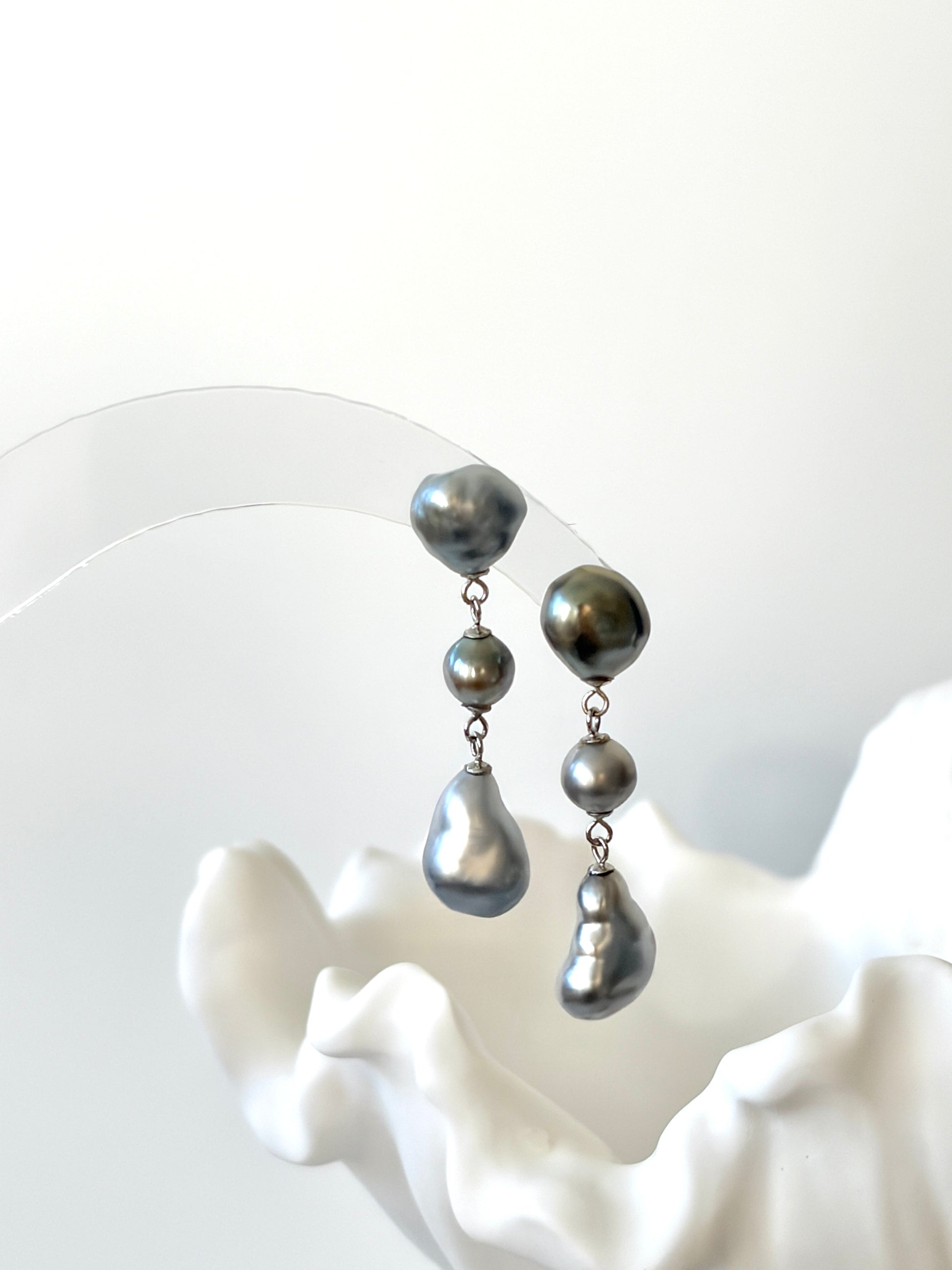 Pair of silver Tahitian Keshi Baroque pearl earrings on a white background