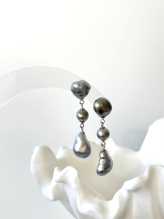 Pair of silver Tahitian Keshi Baroque pearl earrings on a white background