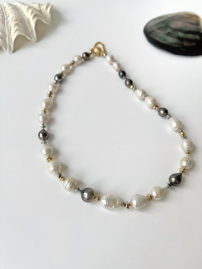 Pearl necklace with black, white and gold beads on a white background