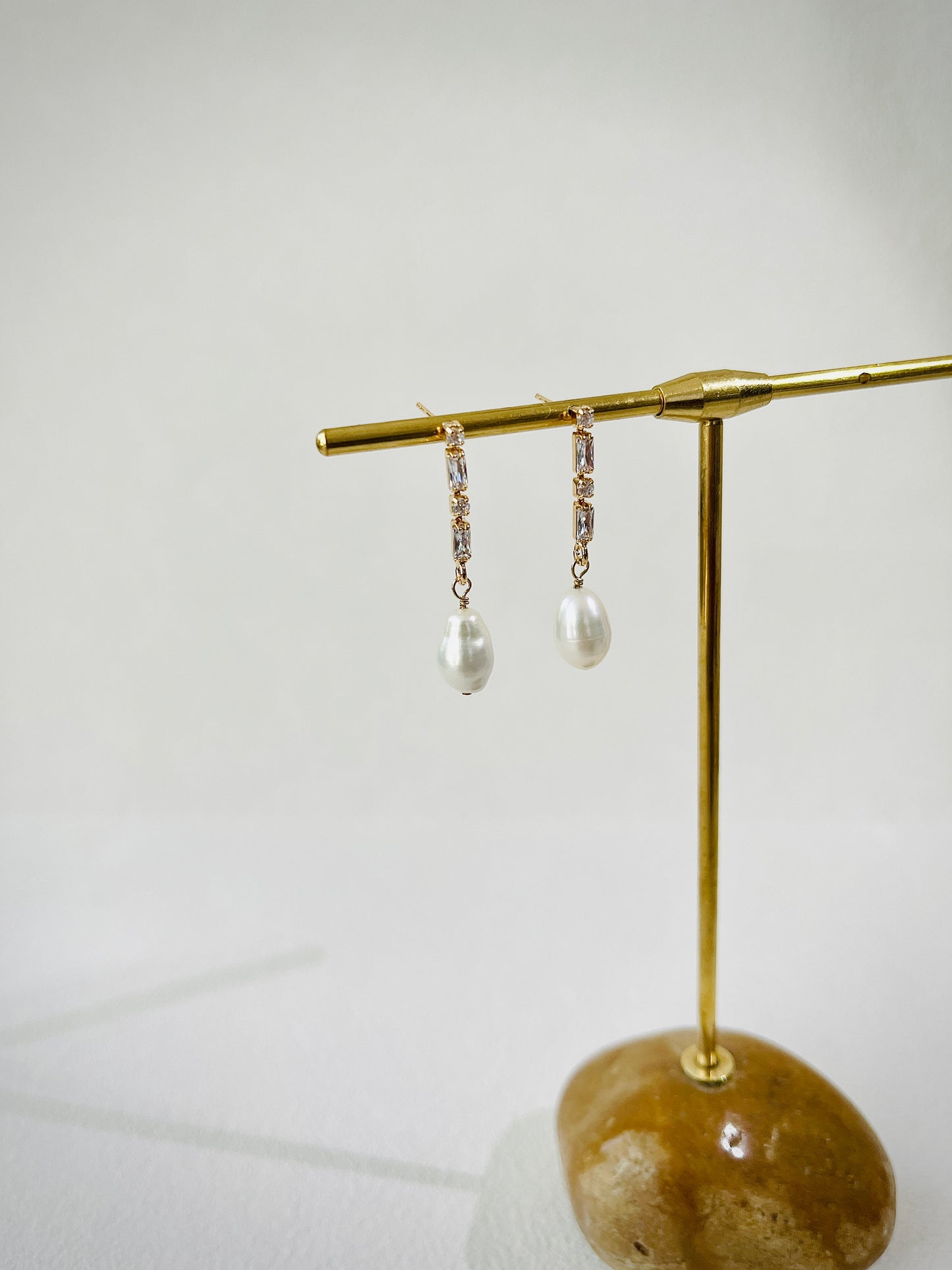 Pair of pearl earrings on a gold stand with a white background