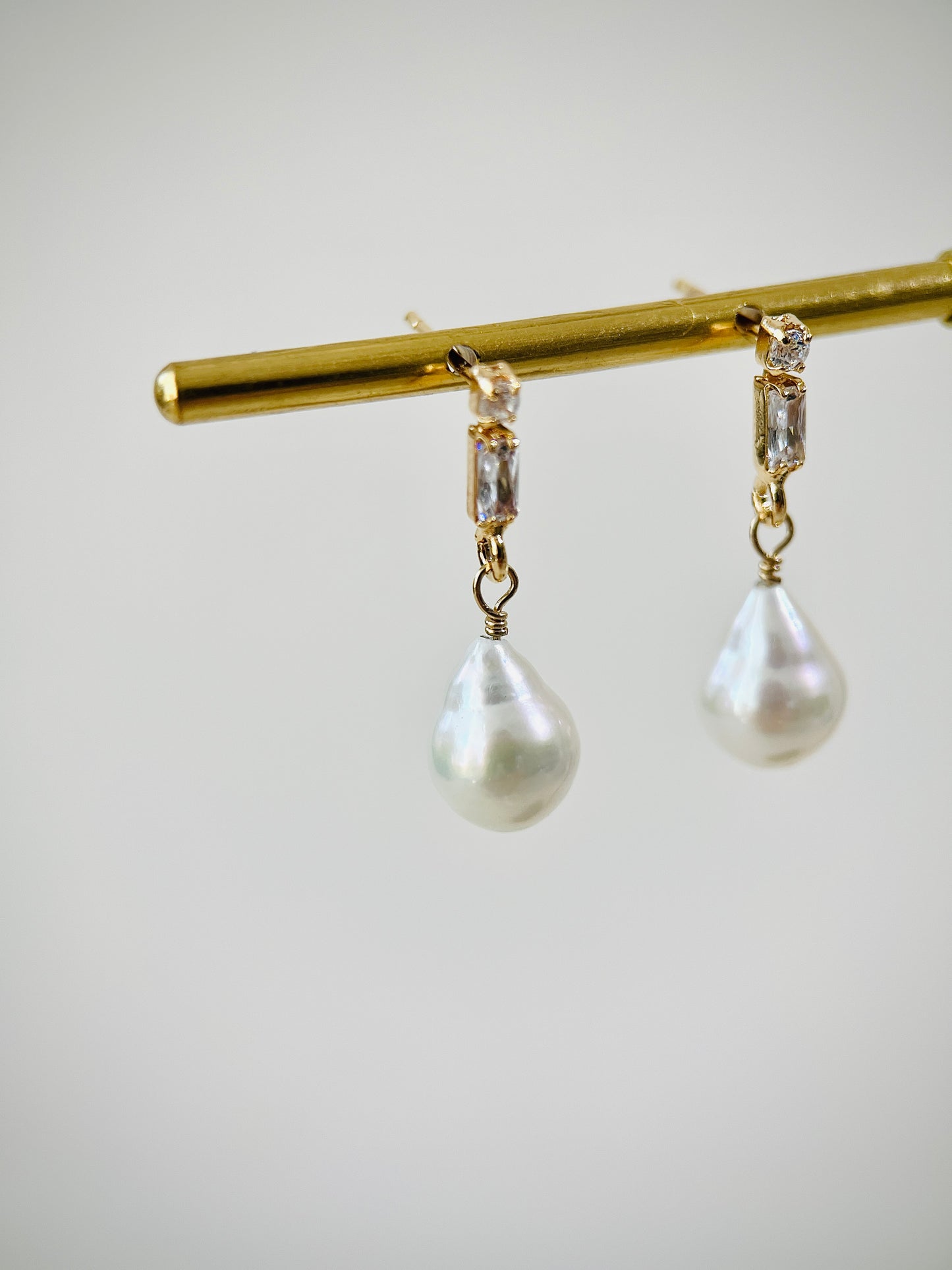 Pearl earrings with gold zircon stud on a white background