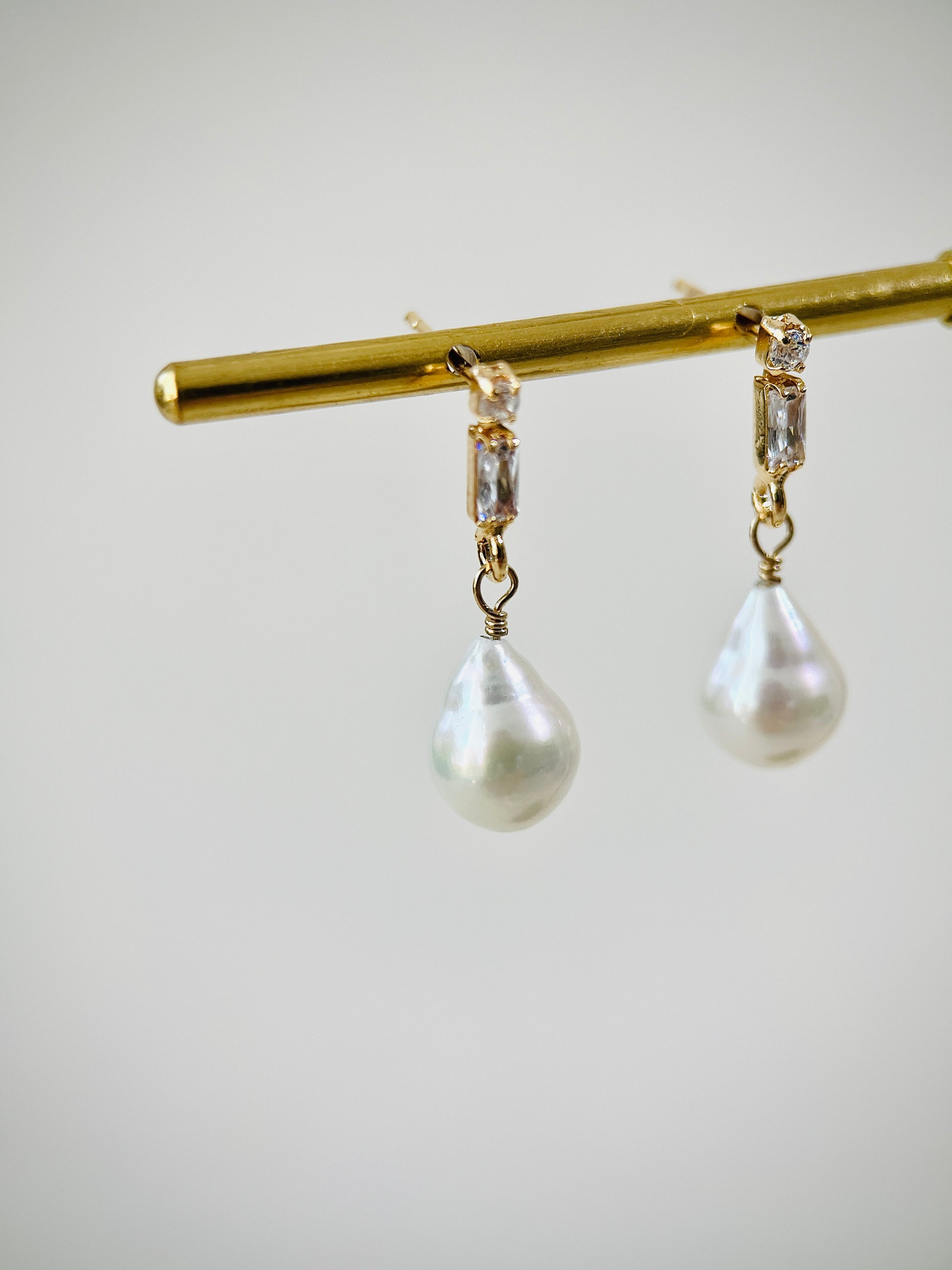 Pearl earrings with gold zircon stud on a white background