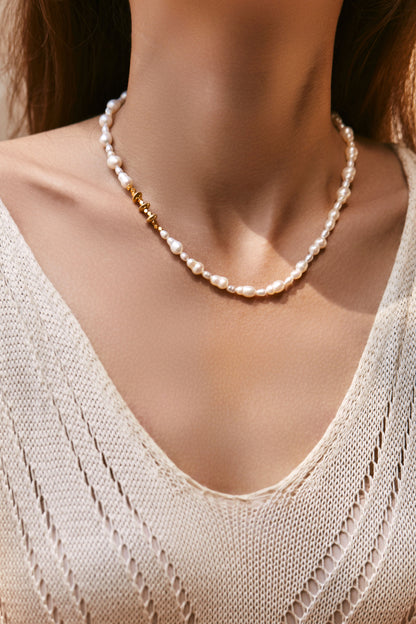 Pearl necklace worn by a person with a neutral background