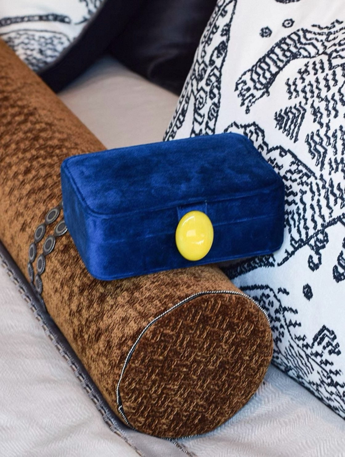 Admiral blue velvet jewelry box with a yellow button on a textured surface