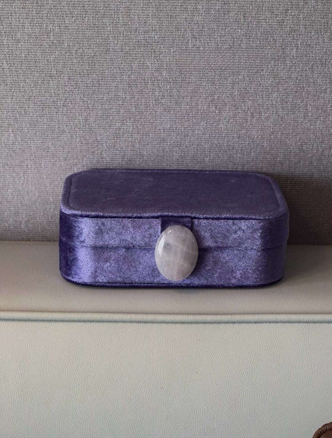 Iris purple velvet jewelry box with a gray stone on a neutral background