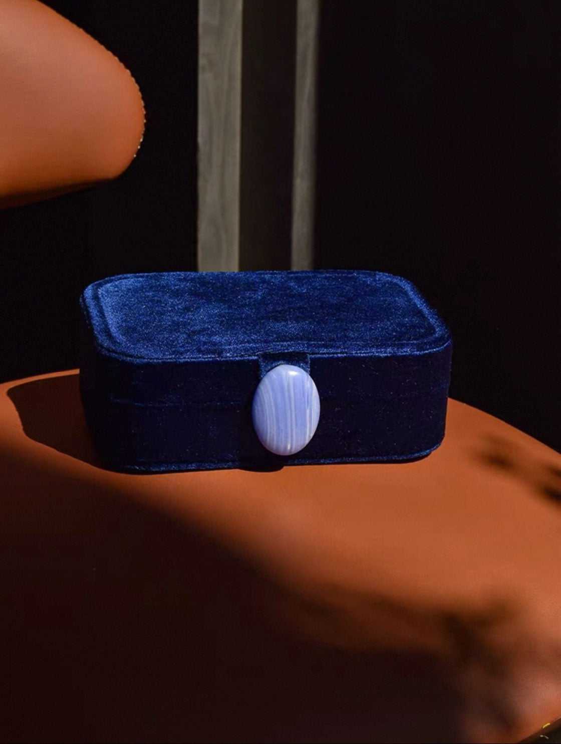 Royal blue velvet jewelry box with a stone on a brown surface