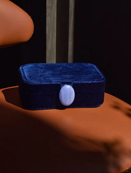Royal blue velvet jewelry box with a stone on a brown surface