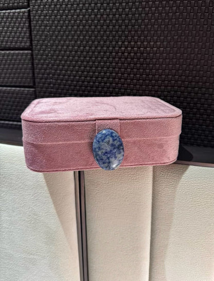 Flamingo pink jewelry box with a blue stone on a textured surface