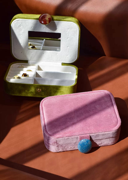 Pink jewelry box with a blue gemstone on a wooden surface