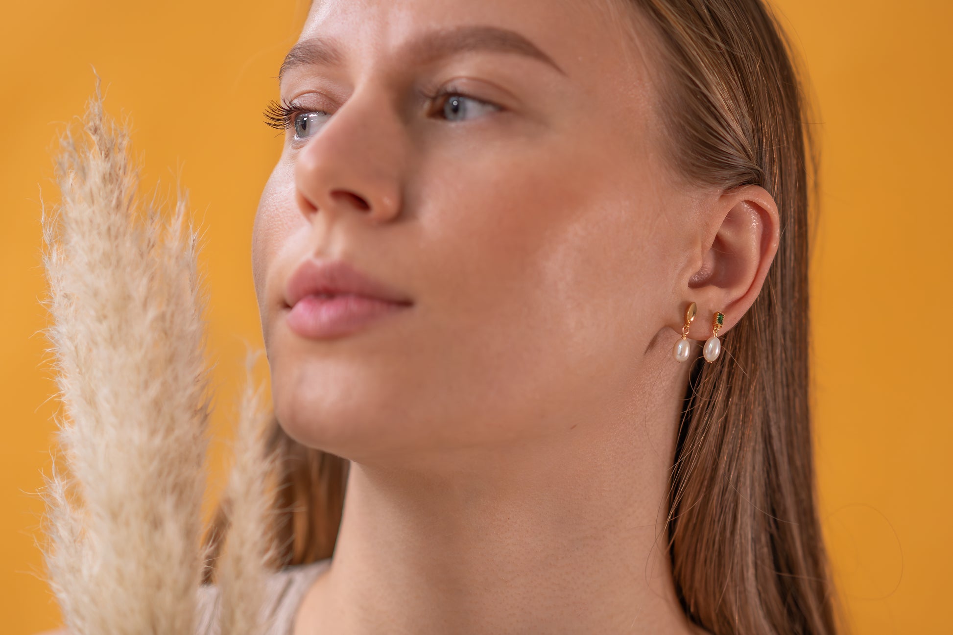 Woman wearing pearl earrings against a yellow background