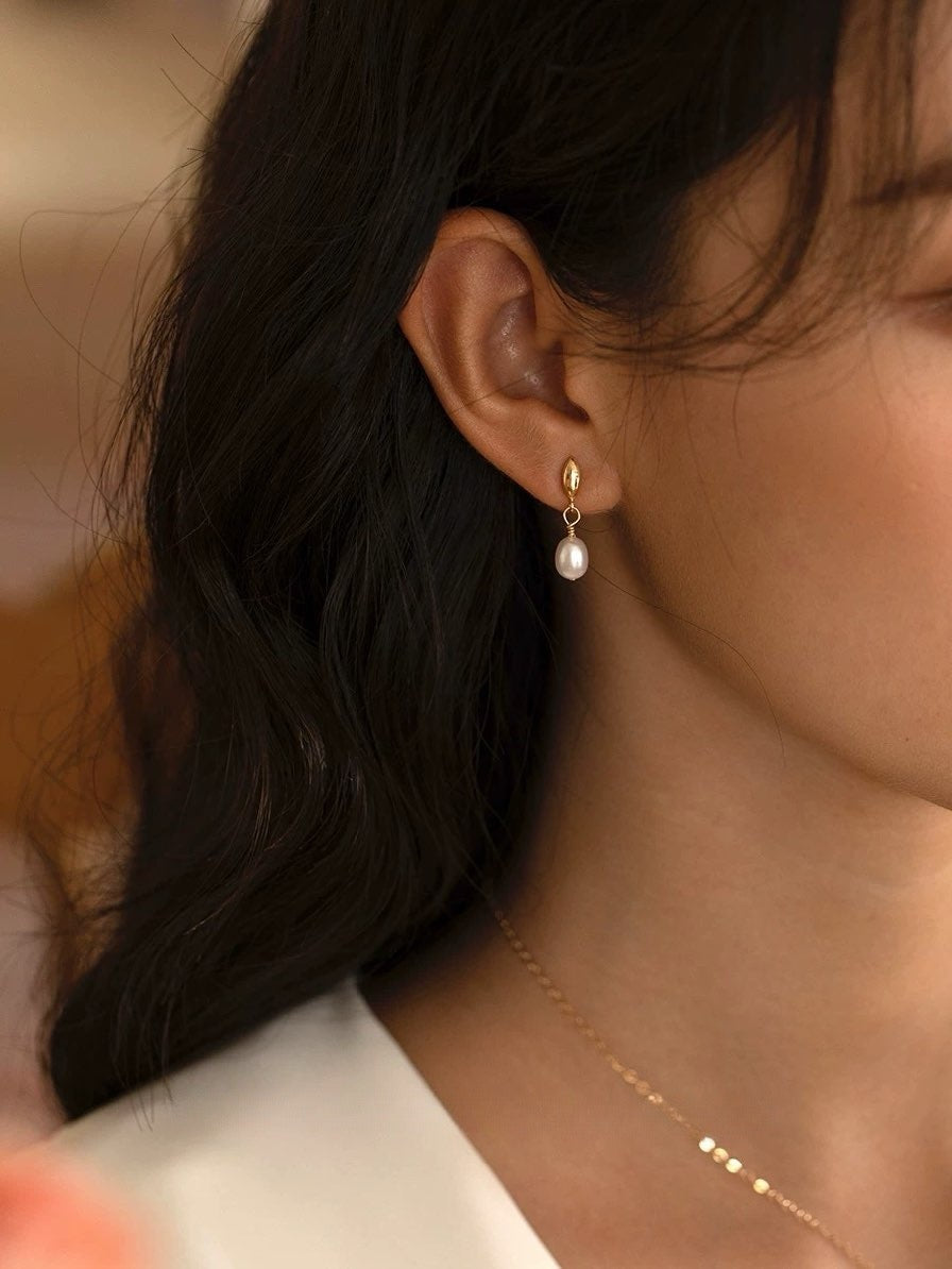 Close-up of an ear wearing a pearl earring with a blurred background