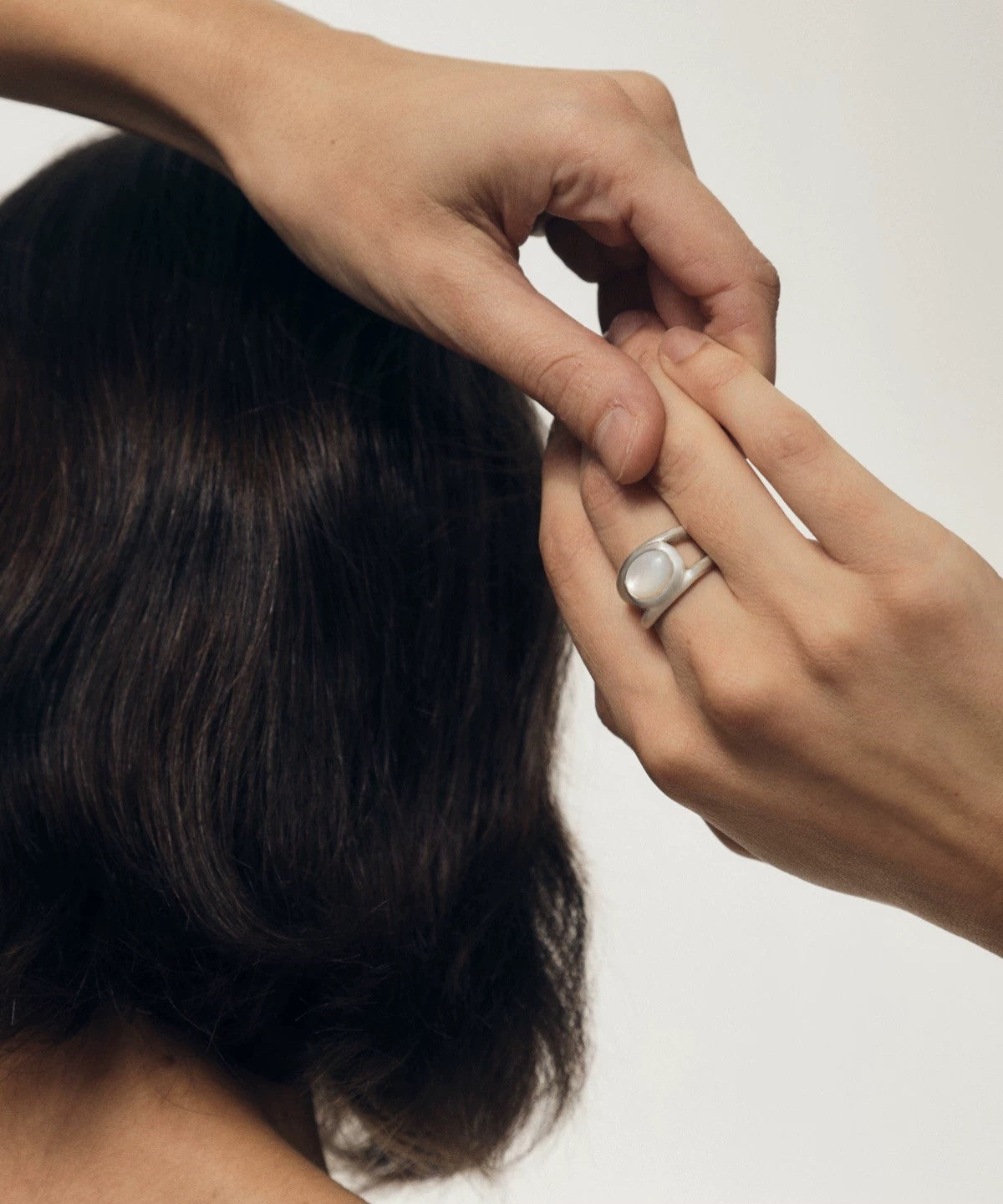 Model wearing a vintage-inspired double layer nacre silver ring while styling hair, highlighting its elegance.