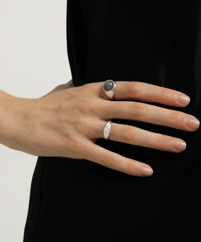 Hand wearing two silver rings on a plain background