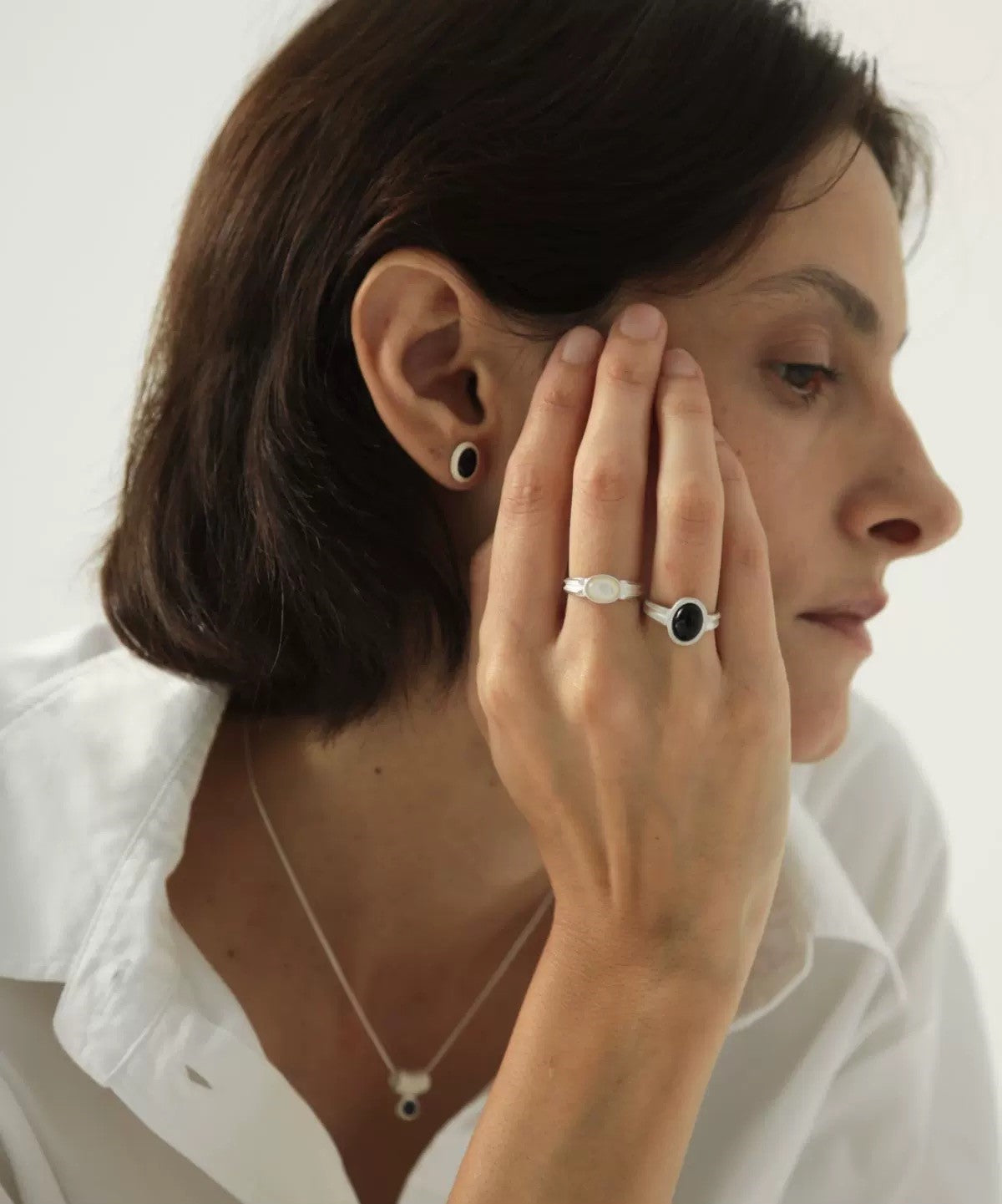 Woman wearing a ring and earrings on a white background