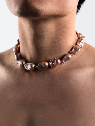 Male model wearing baroque pearl necklace on white background 