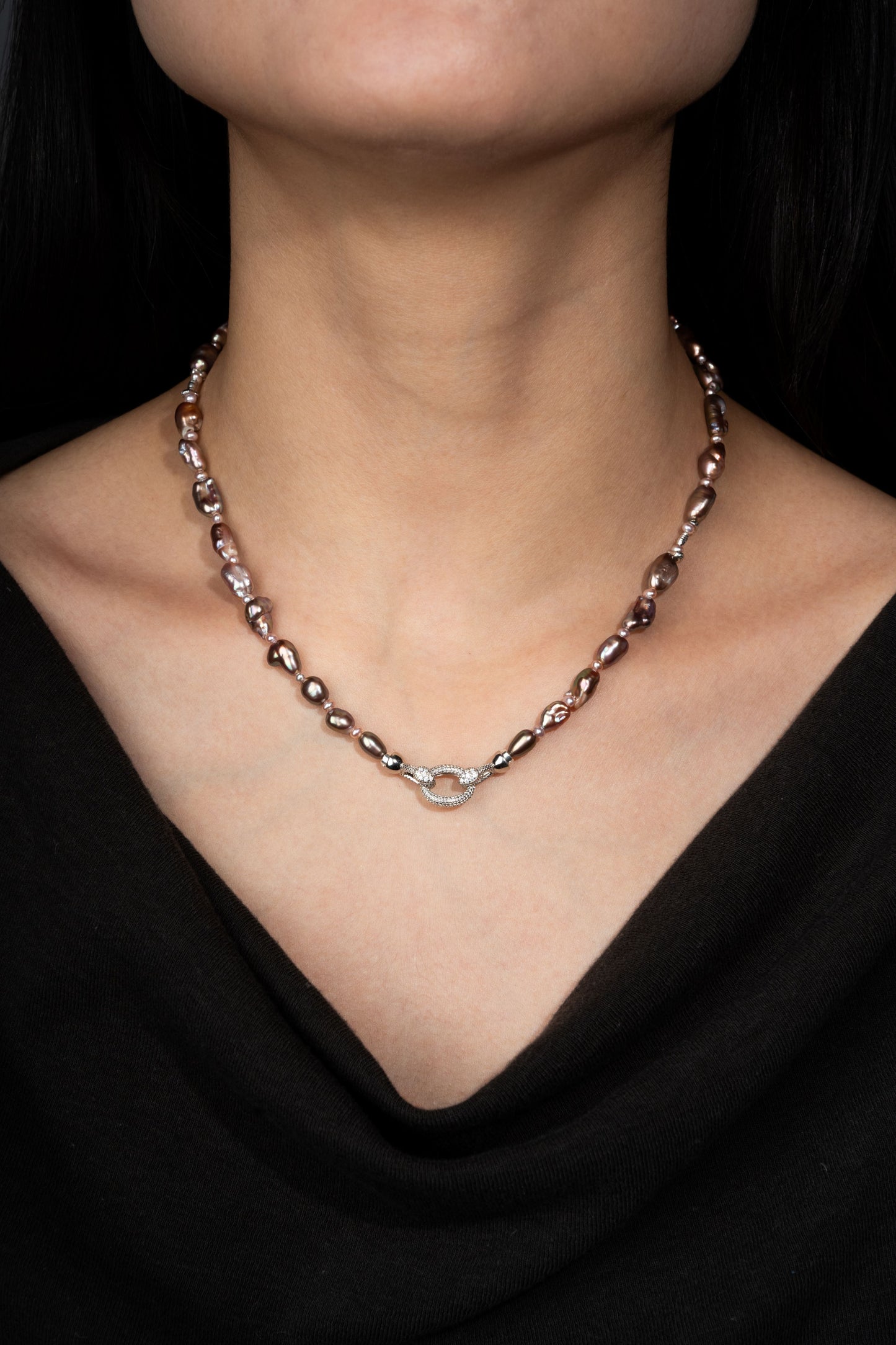 Keshi pearl necklace with a silver clasp on a person wearing a black top against a dark background