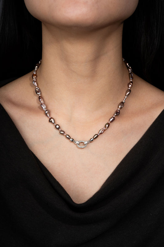 Keshi pearl necklace with a silver clasp on a person wearing a black top against a dark background