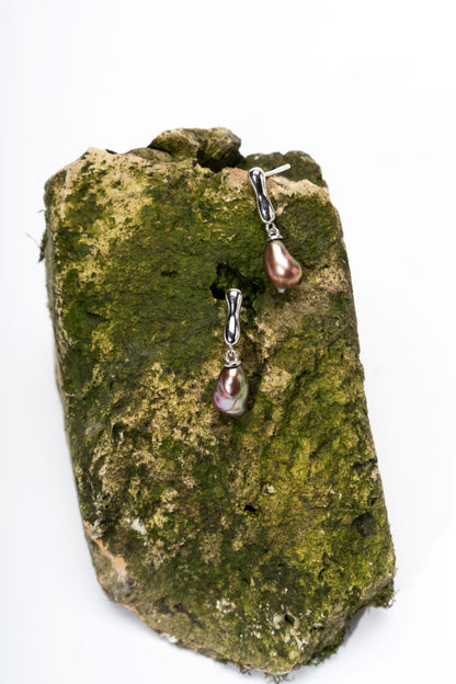Pair of Keshi pearl earrings on a mossy stone background