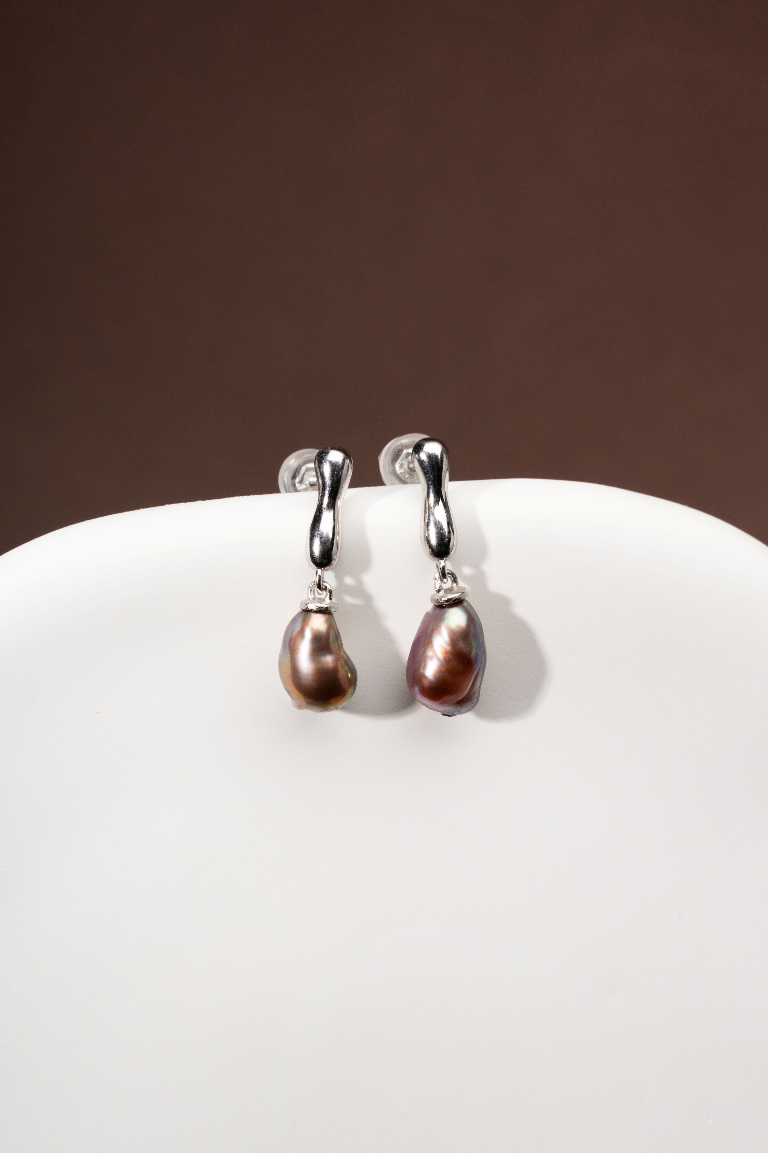 Pair of silver earrings with Keshi freshwater pearls on a white surface