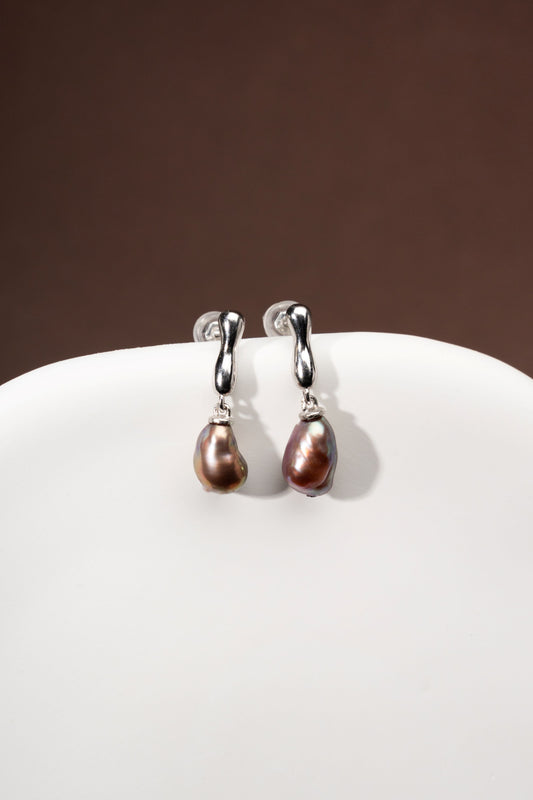 Pair of silver earrings with Keshi freshwater pearls on a white surface