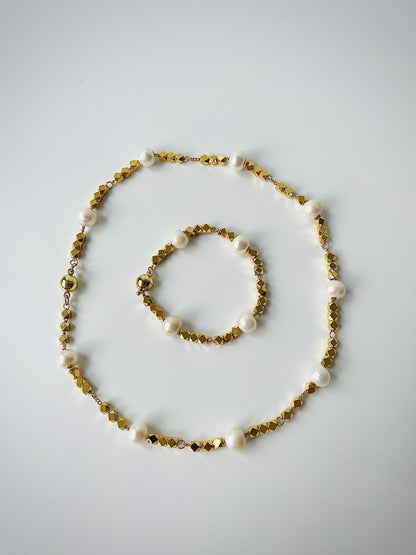 Necklace and bracelet set with gold and pearl beads on a light gray background