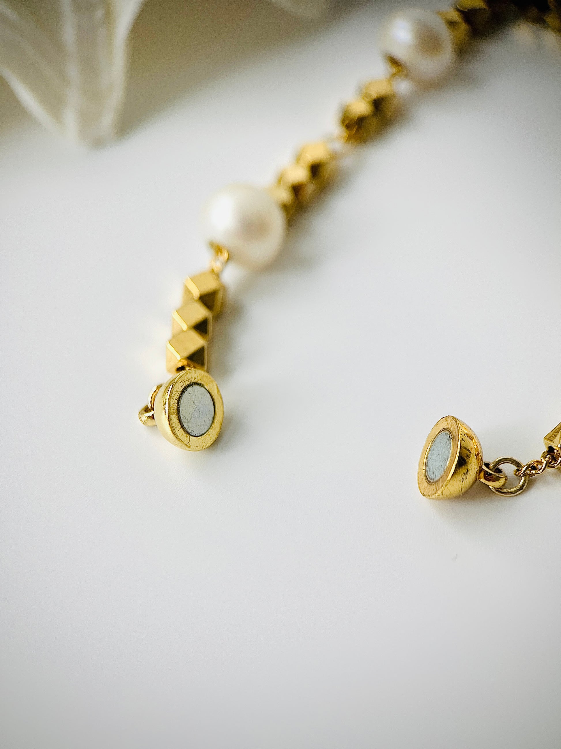 Gold bracelet with pearl beads on a white background