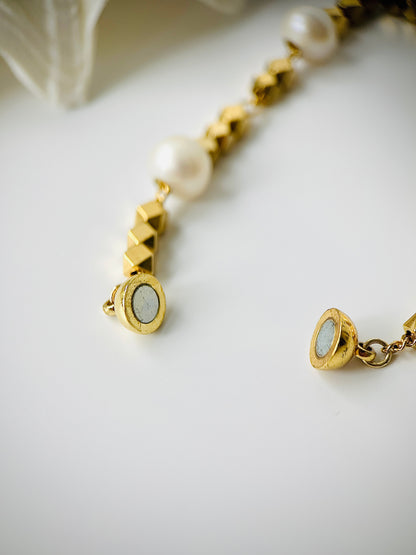 Gold bracelet with pearl beads on a white background