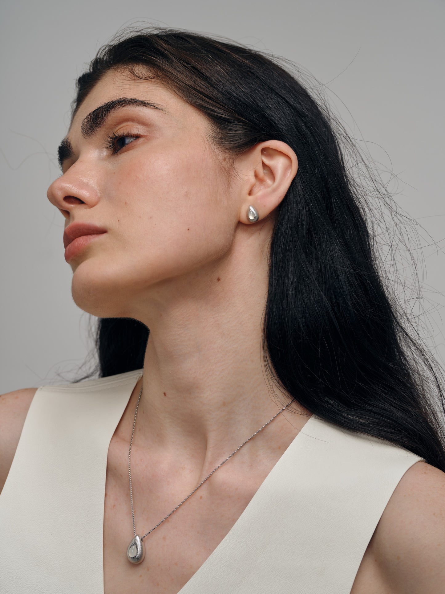 Woman wearing a necklace and earrings with agate gemstones against a neutral background