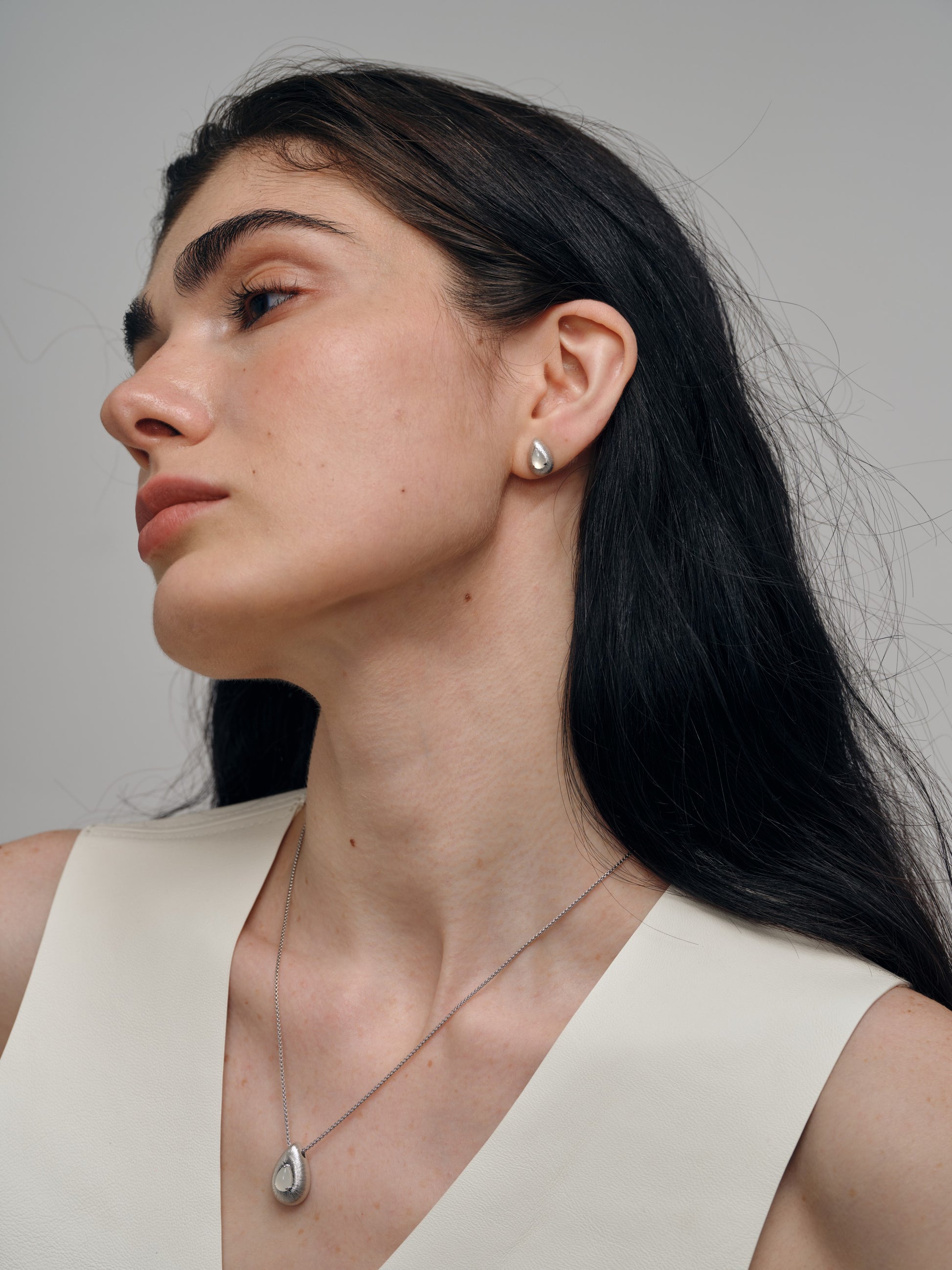 Woman wearing a necklace and earrings with agate gemstones against a neutral background