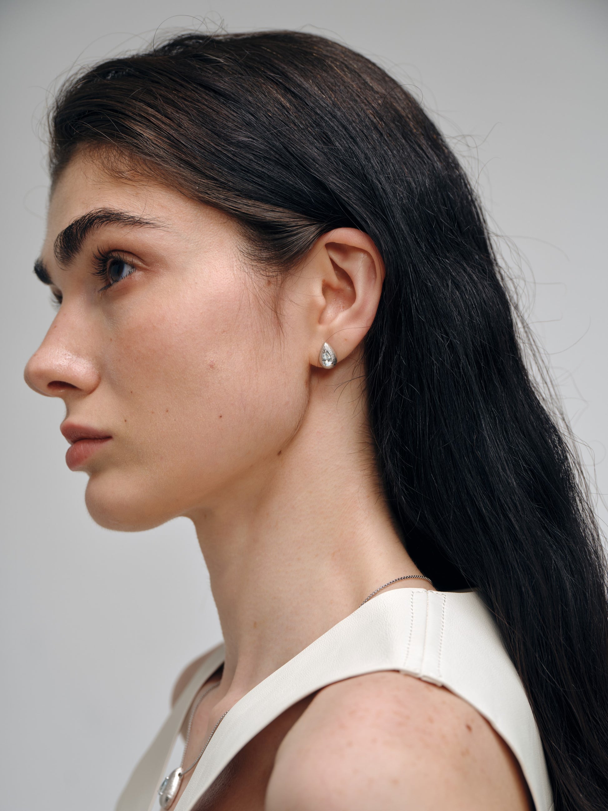 Side profile of a woman with long dark hair wearing a silver necklace and earrings set