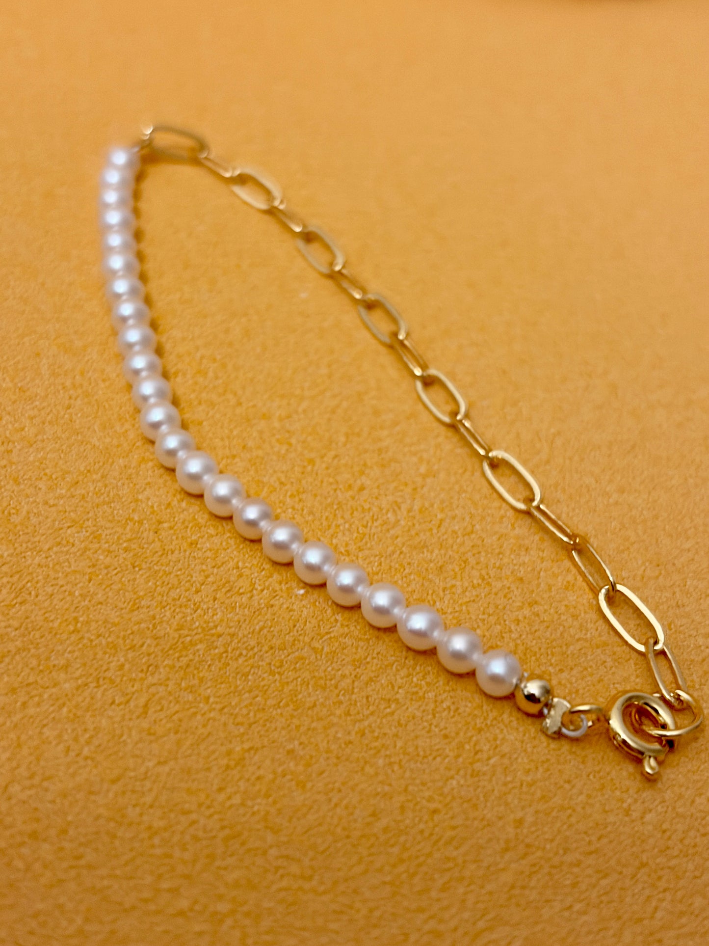 White Freshwater Pearl Bracelet featuring 18k gold-plated silver chain on a textured background.