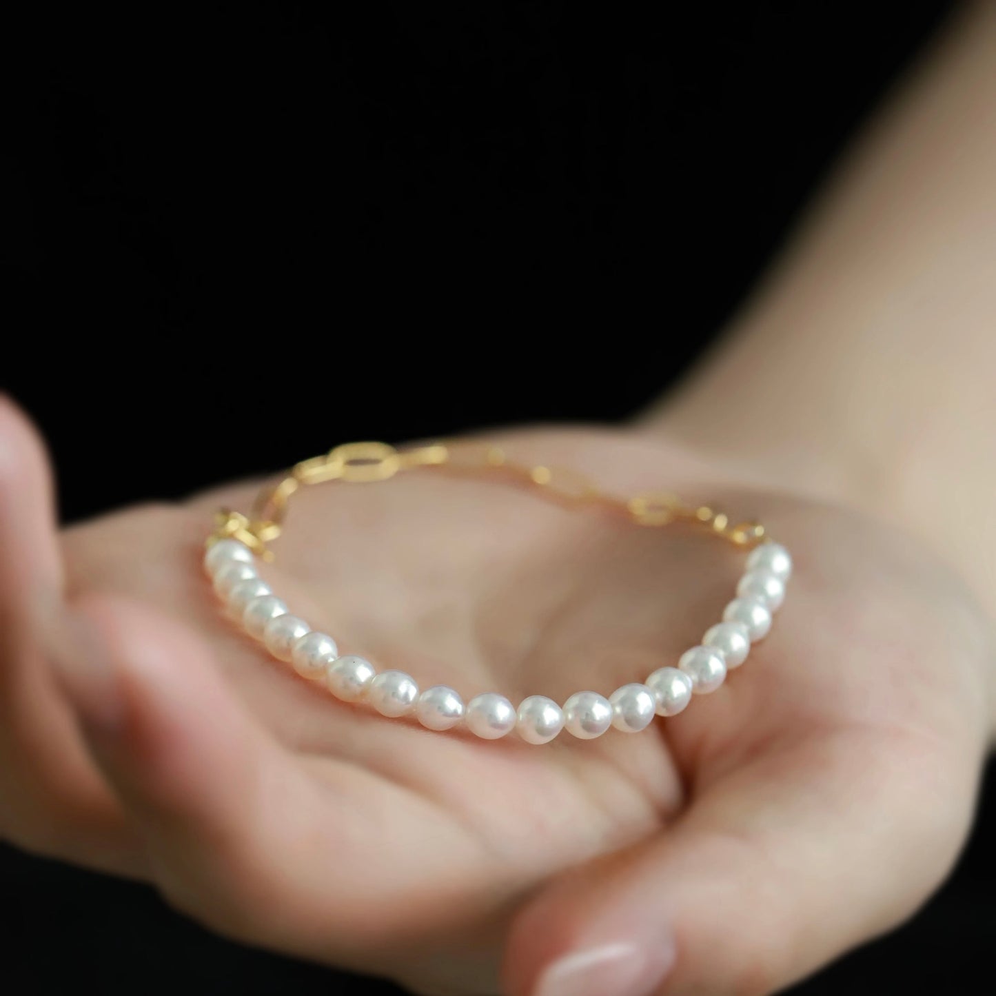 White Freshwater Pearl Bracelet showcased in a hand, featuring lustrous pearls and a gold-plated chain. Perfect for any occasion.