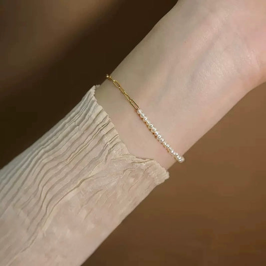 Stylish white freshwater pearl bracelet on a wrist, showcasing elegant pearl design and gold-plated chain accent.