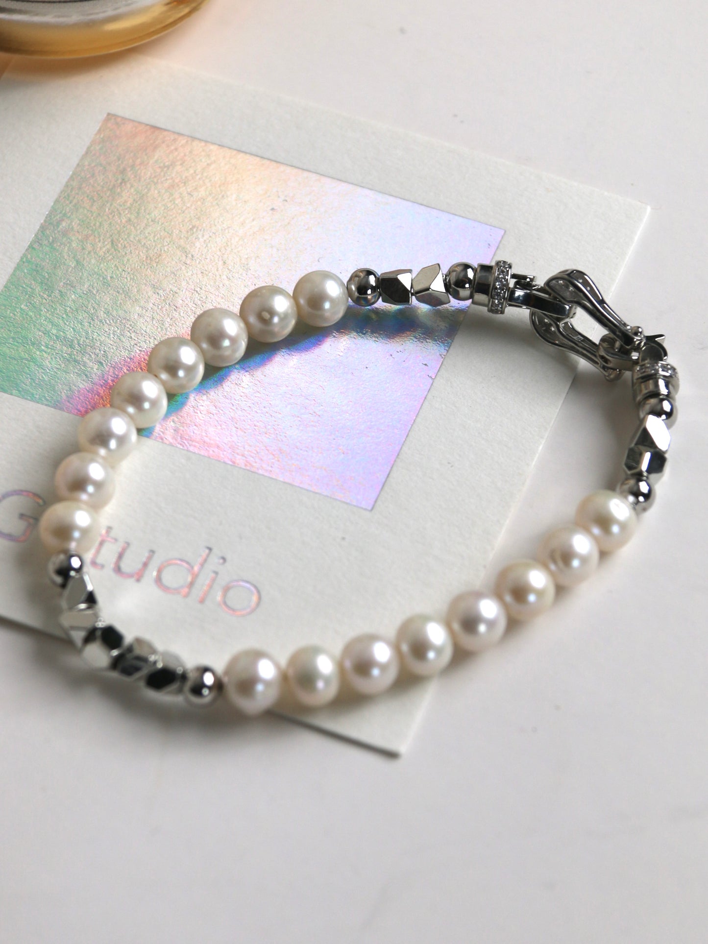 Pearl bracelet for men with silver accents on a white surface with a card in the background