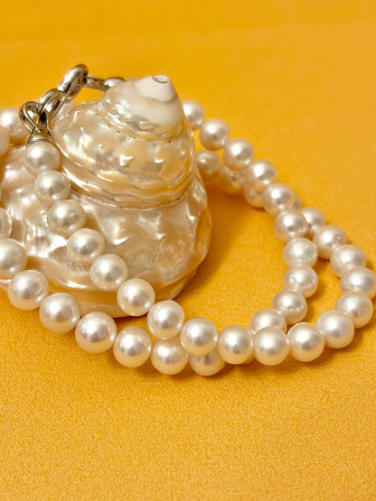 Pearl necklace with a shell-shaped clasp on a yellow background