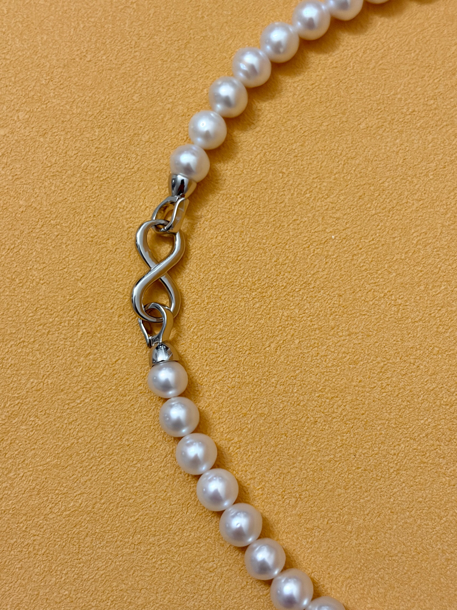 Pearl necklace with a silver clasp on a beige background