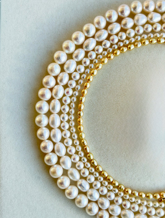 Close-up of pearl and gold necklaces on a light background