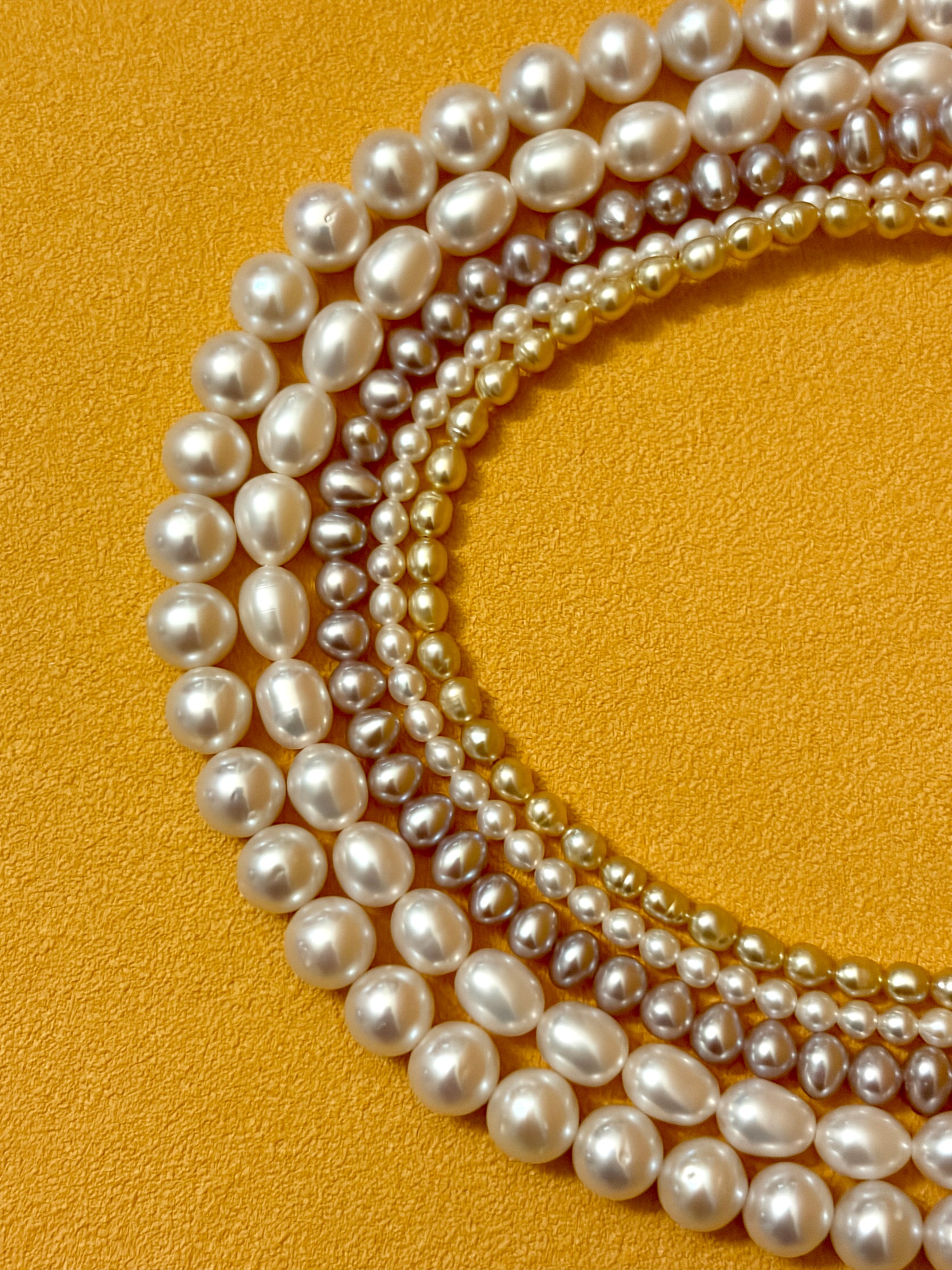 Multiple strands of pearls on a yellow background
