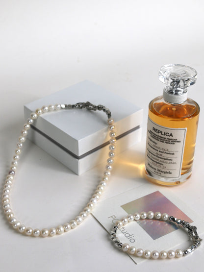 Pearl necklace and bracelet for men with a perfume bottle on a white background