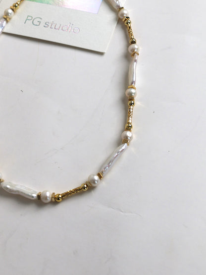 Pearl and gold beaded necklace for men on a white surface with 'PG studio' label.