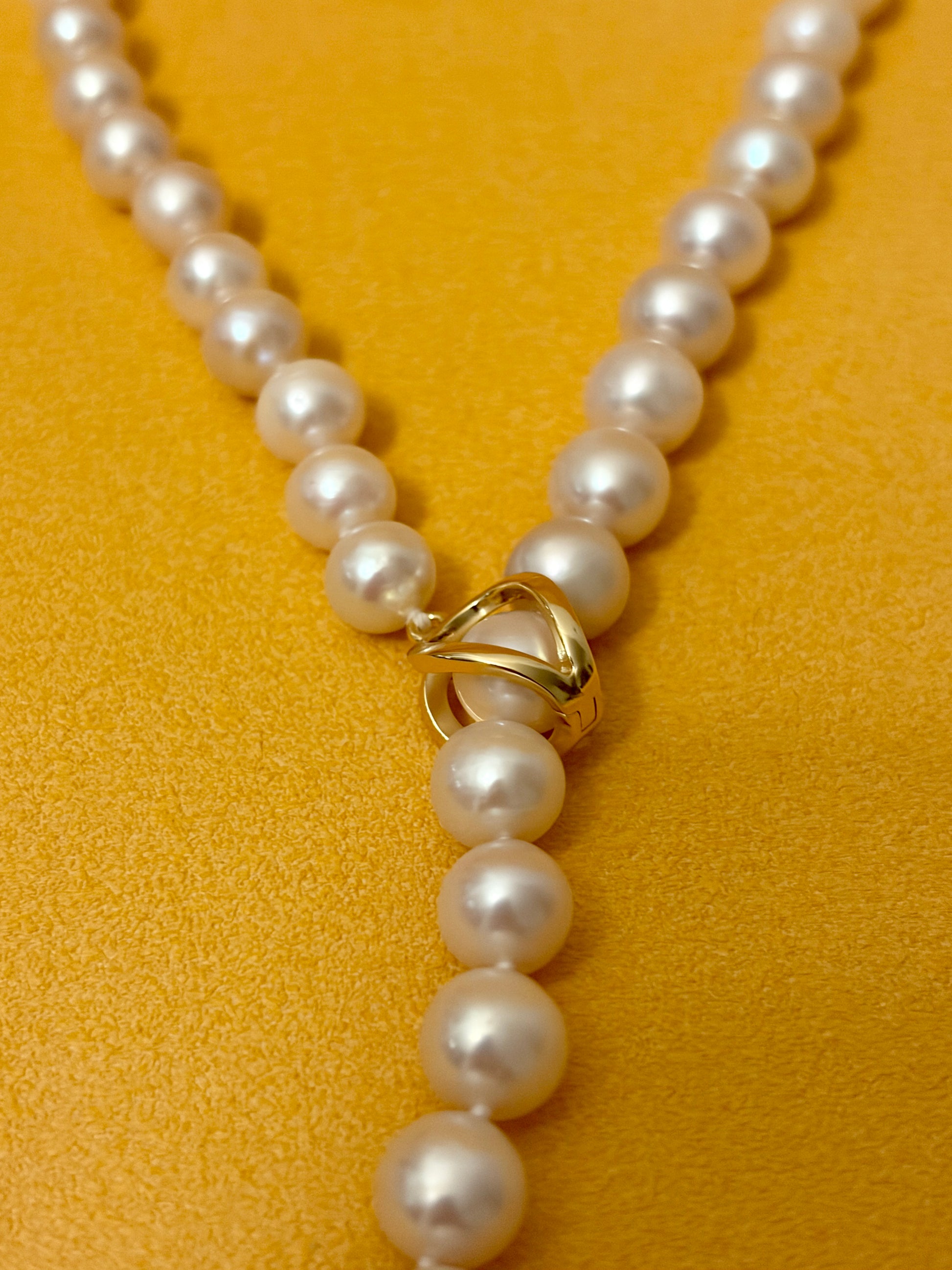 Pearl necklace with a gold clasp on a yellow background