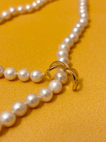 Close-up of the clasp on a White Round Freshwater Pearl Lariat Necklace on a vibrant yellow background.