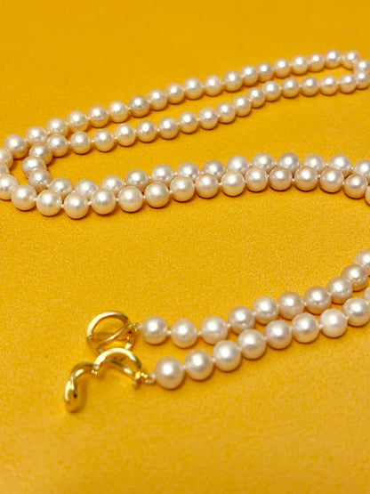 Pearl necklace with a gold clasp on a yellow background