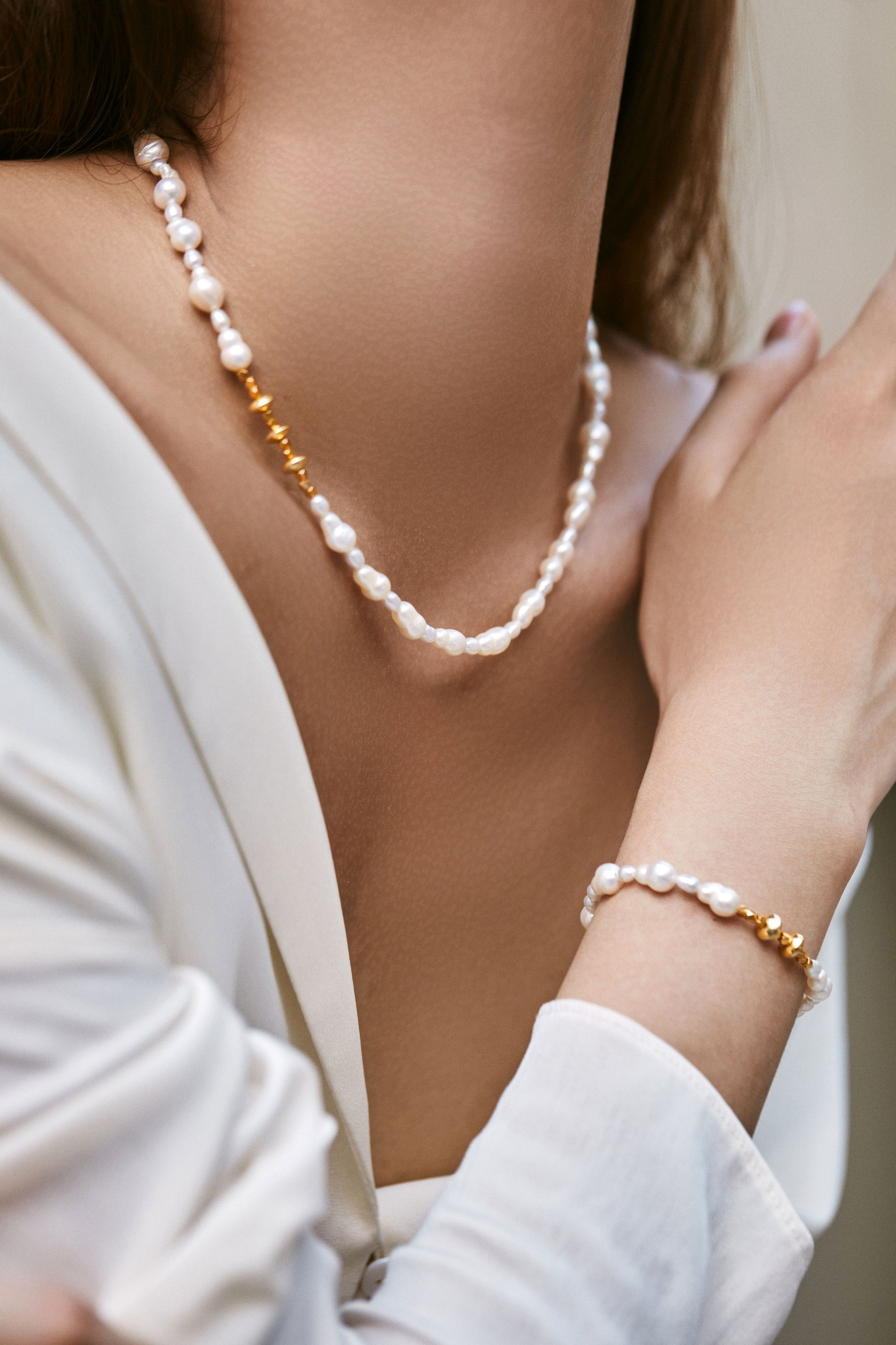 Pearl Bracelet and bracelet on a person wearing a white top.
