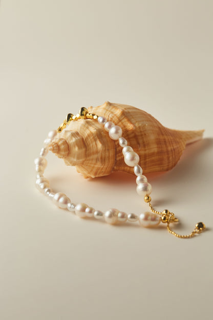 Pearl Bracelet with gold clasp on a seashell against a beige background