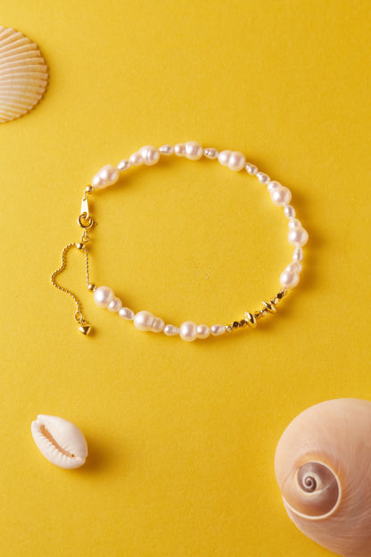 Pearl bracelet with gold accents on a yellow background with shells