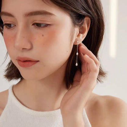 Woman wearing White Freshwater Pearl Chandelier Earrings from the WILD collection, showcasing elegant cascading pearls.